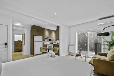 a bedroom with a large white bed and a kitchen at Trendy Open-Space Studio by Jean Talon Market in Montréal