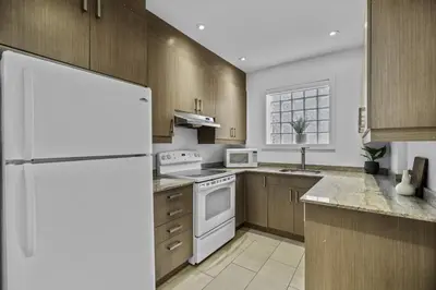 a kitchen with a white refrigerator and wooden cabinets at Trendy Open-Space Studio by Jean Talon Market in Montréal