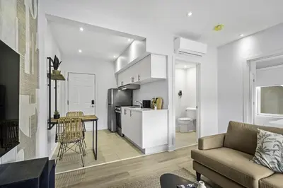 a living room with a couch and a kitchen at Stylish 1-Bedroom Haven by Jean Talon Market in Montréal