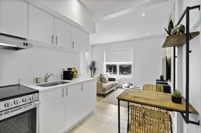 a kitchen and living room with white cabinets and a table at Stylish 1-Bedroom Haven by Jean Talon Market in Montréal
