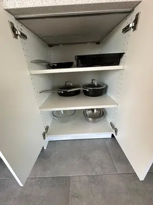 a kitchen with white shelves with pots and pans at Motel Le Refuge in Sherbrooke