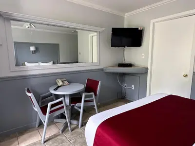 a room with a bed and a table and a mirror at Motel Le Refuge in Sherbrooke