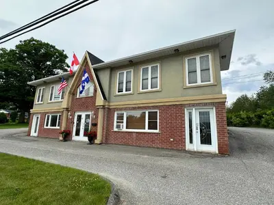 a house with two flags in front of it at Motel Le Refuge in Sherbrooke