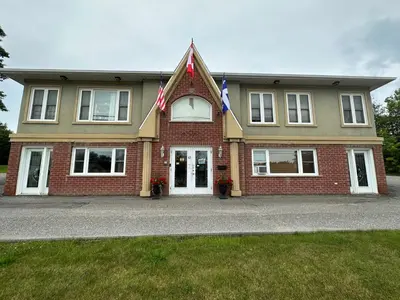 a house with a flag on the front of it at Motel Le Refuge in Sherbrooke