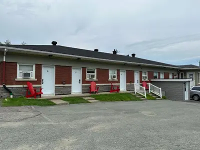 a house with red chairs in a parking lot at Motel Le Refuge in Sherbrooke