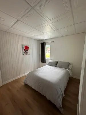 a bedroom with a white bed with a white ceiling at L'Escapade - magnifique appartement in Granby