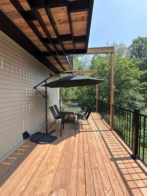 a wooden deck with a table and an umbrella at L'Escapade - magnifique appartement in Granby