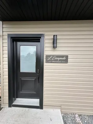 a garage with a black door and a sign on it at L'Escapade - magnifique appartement in Granby