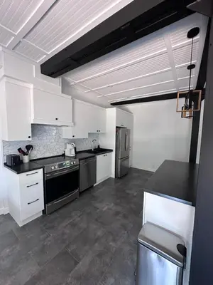 a kitchen with white cabinets and black counter tops at L'Escapade - magnifique appartement in Granby
