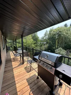 a patio with a grill and a table on a deck at Altitude - magnifique logement in Granby