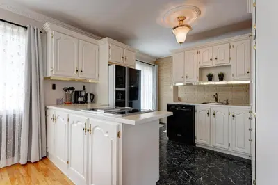 a kitchen with white cabinets and a black dishwasher at 4 Beds Entire House Wifi Parking in Laval-des-Rapides