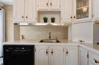 a kitchen with white cabinets and a sink at 4 Beds Entire House Wifi Parking in Laval-des-Rapides