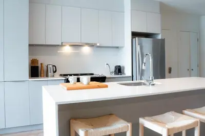 a white kitchen with white cabinets and a sink at Penthouse with pool and parking in Montréal
