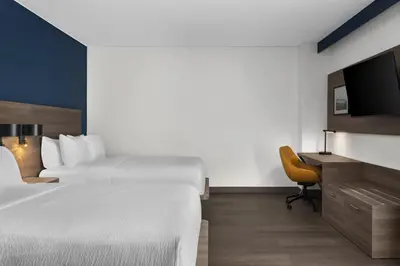 a hotel room with two beds and a desk and a tv at Holiday Inn Express Montreal Airport - St-Laurent by IHG in Montréal