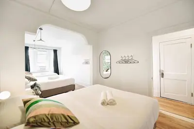 a white bedroom with two beds and a mirror at MTLVacationRentals- Le Clebard in Montréal