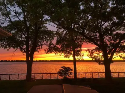 a sunset over a body of water with trees at Spacious Lakefront Champlain lake with SPA in Venise-en-Québec