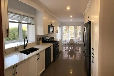 a kitchen with white cabinets and a black refrigerator at Spacious Lakefront Champlain lake with SPA in Venise-en-Québec