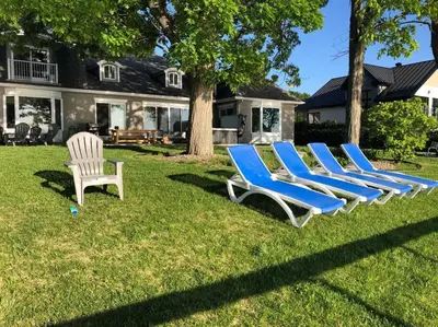 a group of lounge chairs sitting in the grass at Spacious Lakefront Champlain lake with SPA in Venise-en-Québec