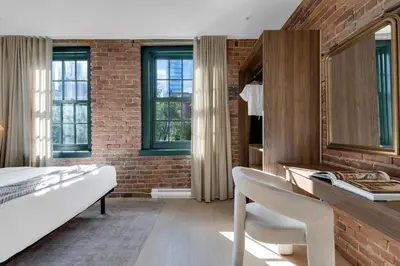 a bedroom with a bed and a brick wall at The Mercer Boutique Hotel in Montréal