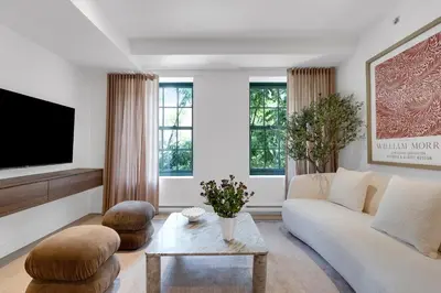 a living room with a white couch and a tv at The Mercer Boutique Hotel in Montréal