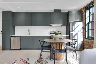 a kitchen with black cabinets and a table with chairs at The Mercer Boutique Hotel in Montréal