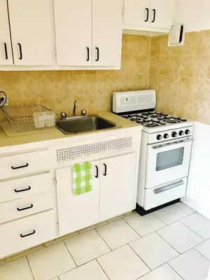 a white kitchen with a sink and a stove at Stylish Montreal Apartment Comfortable Stay in the Golden Square Mile in Montréal