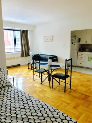 a living room with a table and chairs and a kitchen at Stylish Montreal Apartment Comfortable Stay in the Golden Square Mile in Montréal