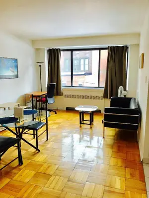 a living room with furniture and a large window at Stylish Montreal Apartment Comfortable Stay in the Golden Square Mile in Montréal