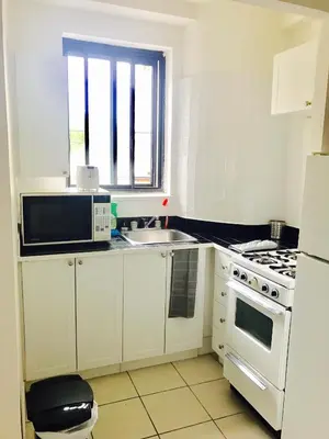 a white kitchen with a sink and a stove at Stylish Montreal Apartment Comfortable Stay in the Golden Square Mile in Montréal
