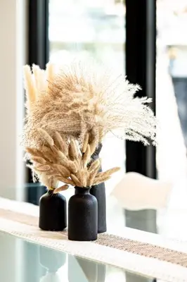 two black vases filled with dried grass on a table at Amazing 4-Bedrooms in Homa Montreal 20 in Montréal