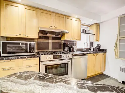 a kitchen with wooden cabinets and stainless steel appliances at Amazing 4-Bedrooms in Homa Montreal 20 in Montréal