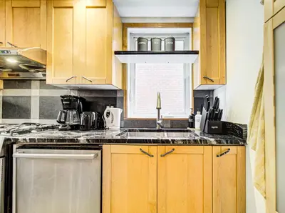 a kitchen with wooden cabinets and a sink and a window at Amazing 4-Bedrooms in Homa Montreal 20 in Montréal