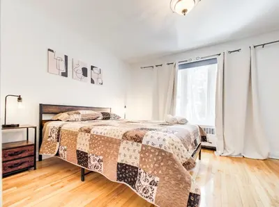 a white bedroom with a bed and a window at Amazing 4-Bedrooms in Homa Montreal 20 in Montréal