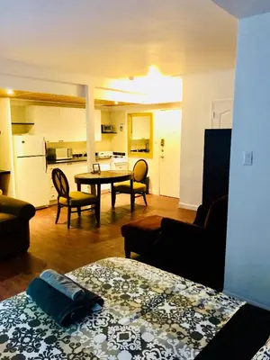 a living room with a table and chairs and a kitchen at Stylish Montreal Apartment Comfortable Stay in the Golden Square Mile in Montréal