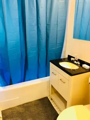 a bathroom with a sink and a blue shower curtain at Stylish Montreal Apartment Comfortable Stay in the Golden Square Mile in Montréal