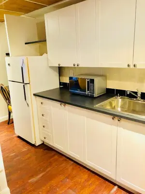 a kitchen with white cabinets and a sink and a refrigerator at Stylish Montreal Apartment Comfortable Stay in the Golden Square Mile in Montréal