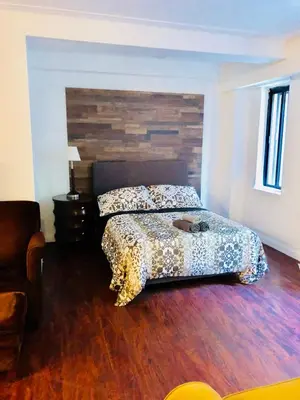 a bedroom with a bed with a wooden floor at Stylish Montreal Apartment Comfortable Stay in the Golden Square Mile in Montréal