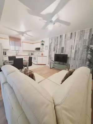 a living room with a white couch and a kitchen at Le cosy for familys, home work in Longueuil