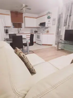 a living room with a white couch and a kitchen at Le cosy for familys, home work in Longueuil