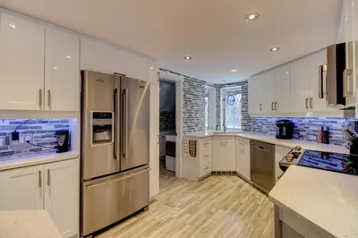 a kitchen with white cabinets and a stainless steel refrigerator at L'Ile Enchantée in Trois-Rivières