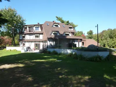 a large house sitting on top of a lush green yard at L'Ile Enchantée in Trois-Rivières