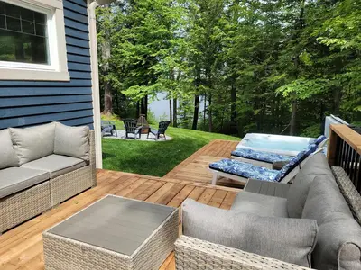 a patio with a couch and a table on a deck at View and access to Lake Orford - Spa - Australe in Austin