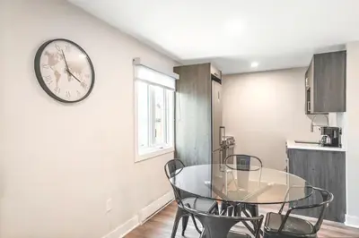 a dining room with a glass table and a clock on the wall at Fancy 3 BDR in Heart of Plateau B in Montréal