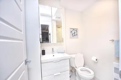 a white bathroom with a toilet and a sink at Elegant 3BDR in Heart Of Plateau 8B in Montréal