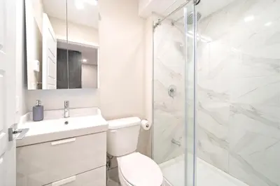 a white bathroom with a toilet and a shower at Elegant 1BDR in Heart Of Plateau B in Montréal