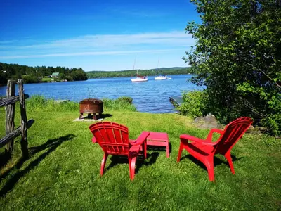 two red chairs and a table next to a lake at Chalet Esmeralda in Piopolis