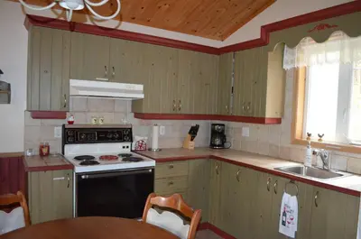 a kitchen with a stove and a sink and a table at Chalet Esmeralda in Piopolis
