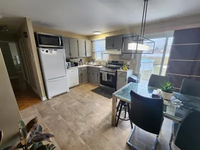 a kitchen with white appliances and a table with chairs at Cozy 3-Bedroom Haven, Private Pool & Parking ! in Longueuil