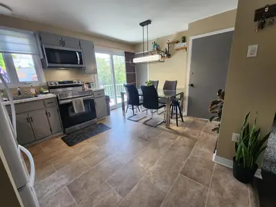 a kitchen and dining room with a table and chairs at Cozy 3-Bedroom Haven, Private Pool & Parking ! in Longueuil
