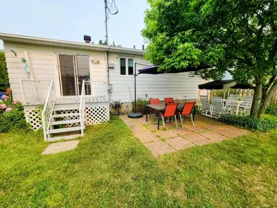 a house with a table and chairs in the yard at Cozy 3-Bedroom Haven, Private Pool & Parking ! in Longueuil
